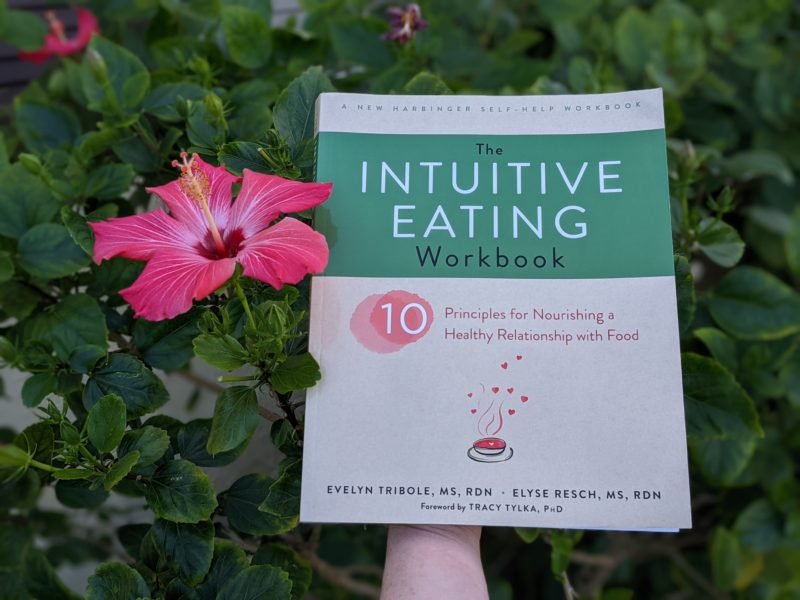 The best books about food and faith Erin holding her pick for the best intuitive eating books - The Intuitive Eating Workbook